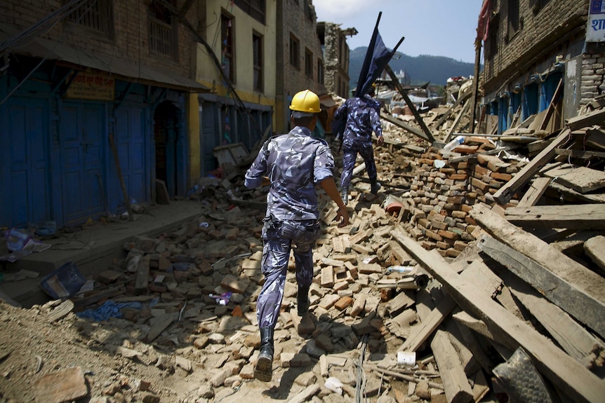 Nepalese police personnel run to rescue earthquake victim