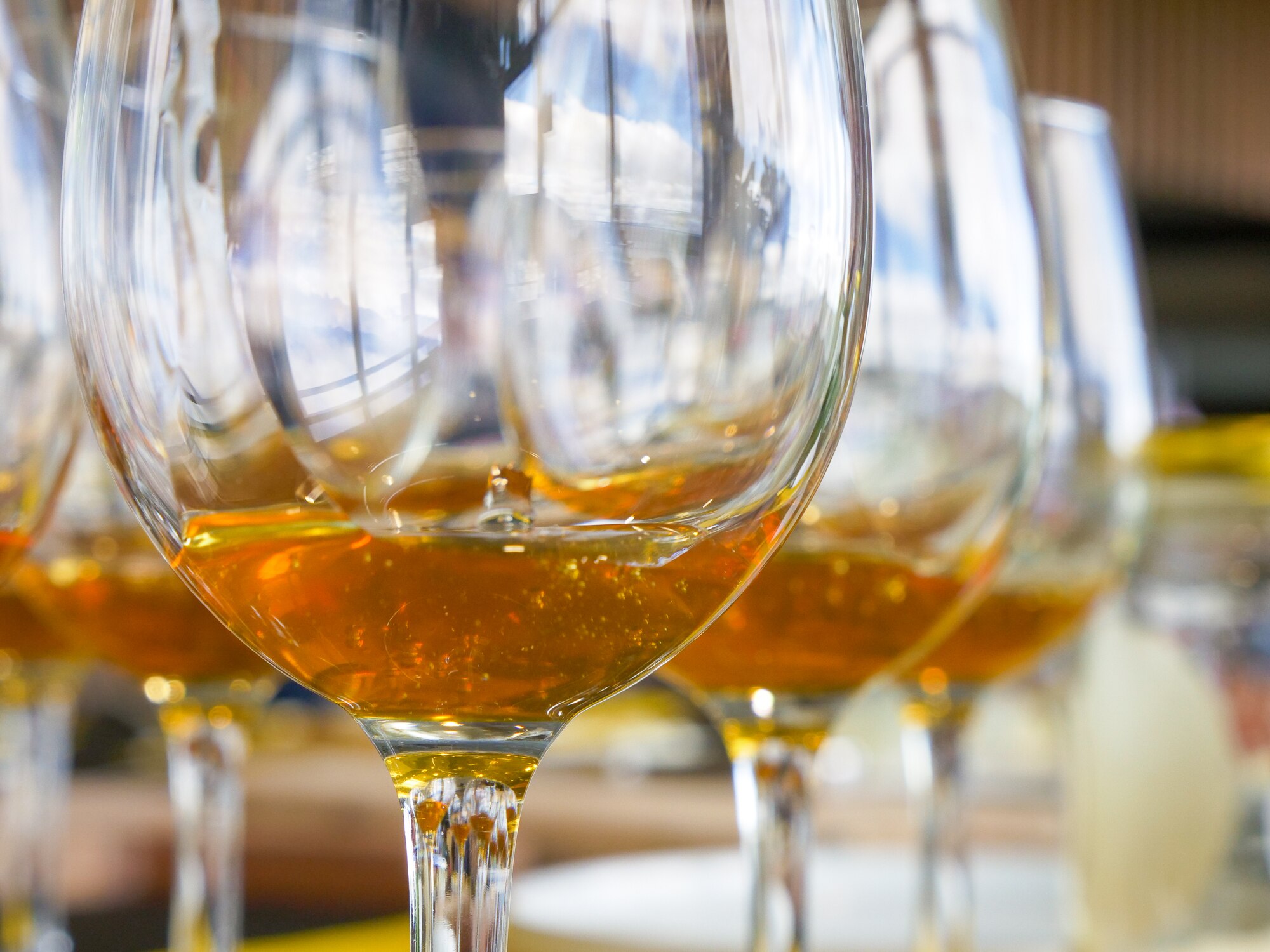 A row of wine glasses containing golden honey. 
