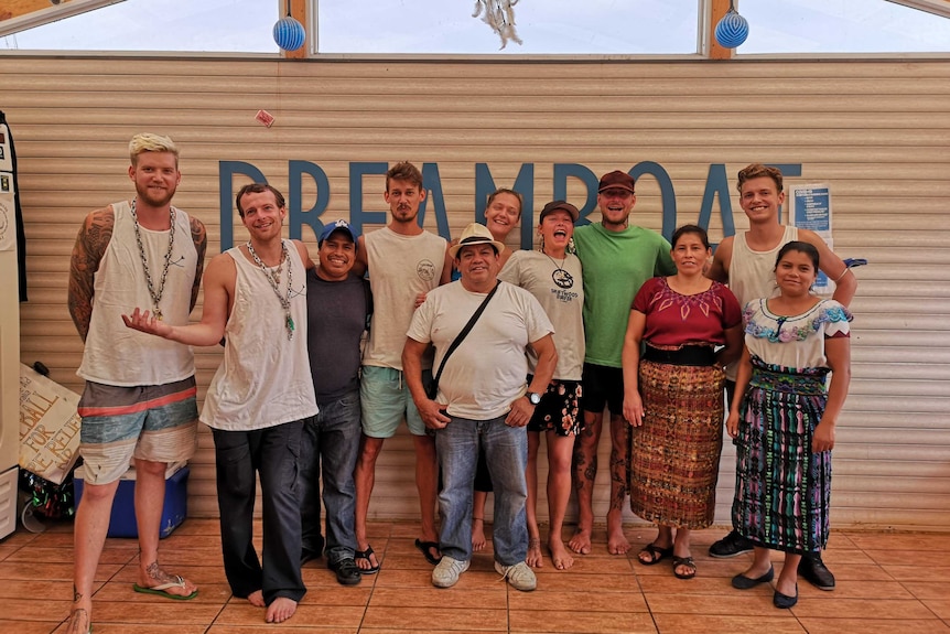 A group of people wearing singlets and summer clothing pose for a photo