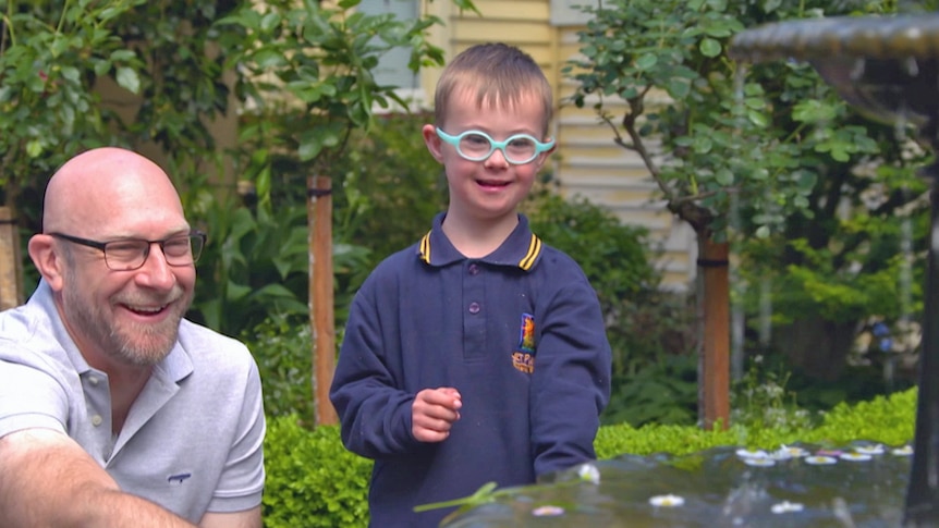 A child with special needs and a man enjoy looking at a water feature in a garden
