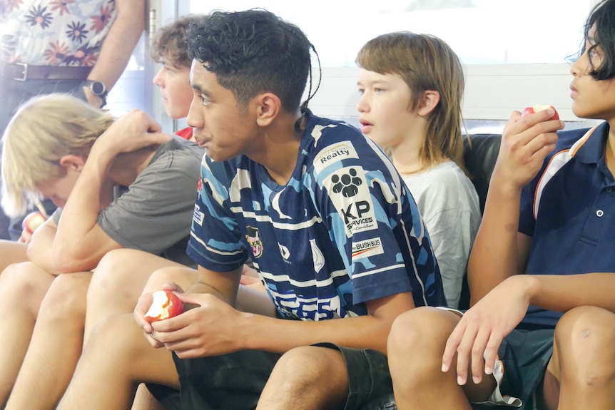 A group of male teenagers sitting on a couch in discussion.