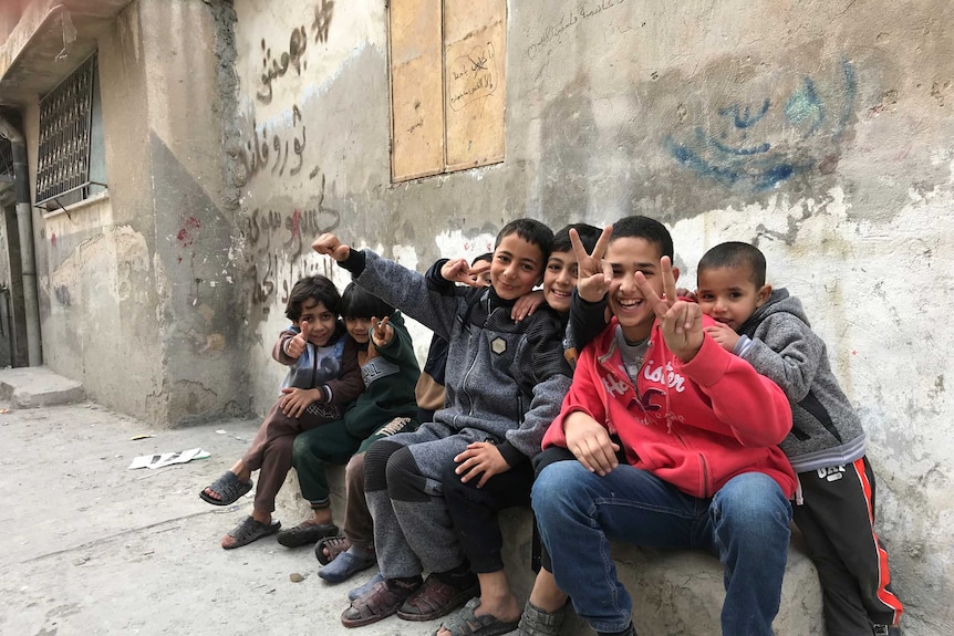 Kids sit together and make peace signs with their hands in Baqa'a Palestinian refugee camp outside of Amman in Jordan.