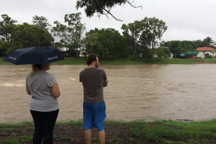 People watch floodwaters rise in Kedron Brook.