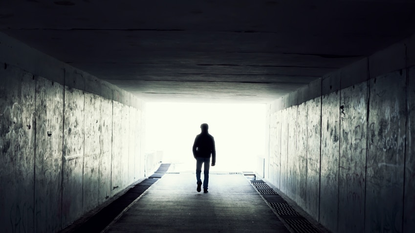 A man walks through a dark tunnel.