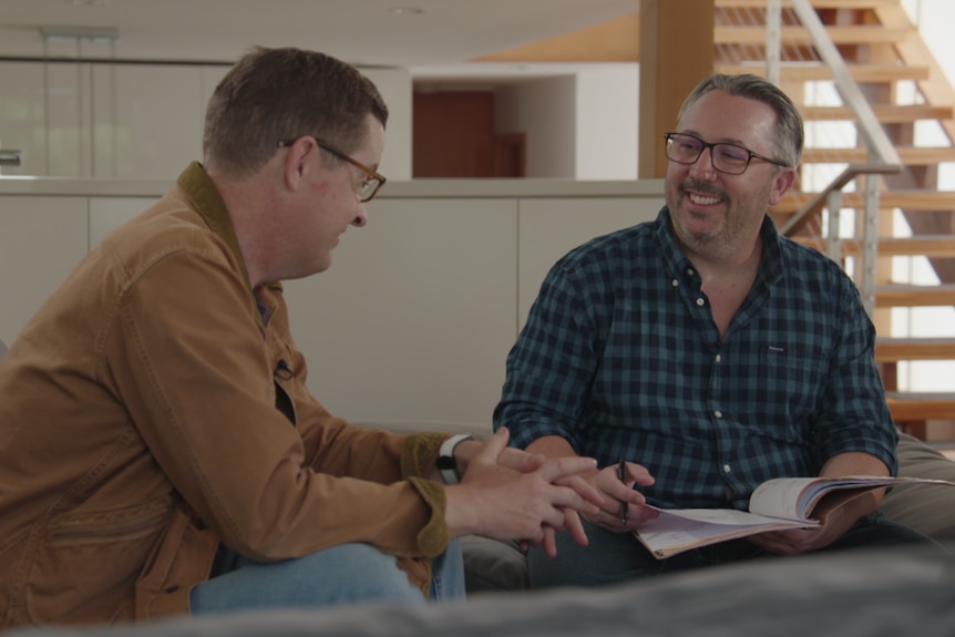 Two men sit on a couch talking