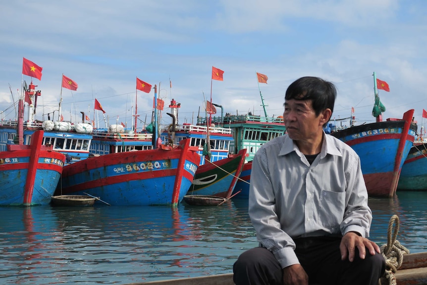 President of the Ly Son Fishermen’s Association, Nguyen Qua Chinh sits in front of fleet of fishing boats.