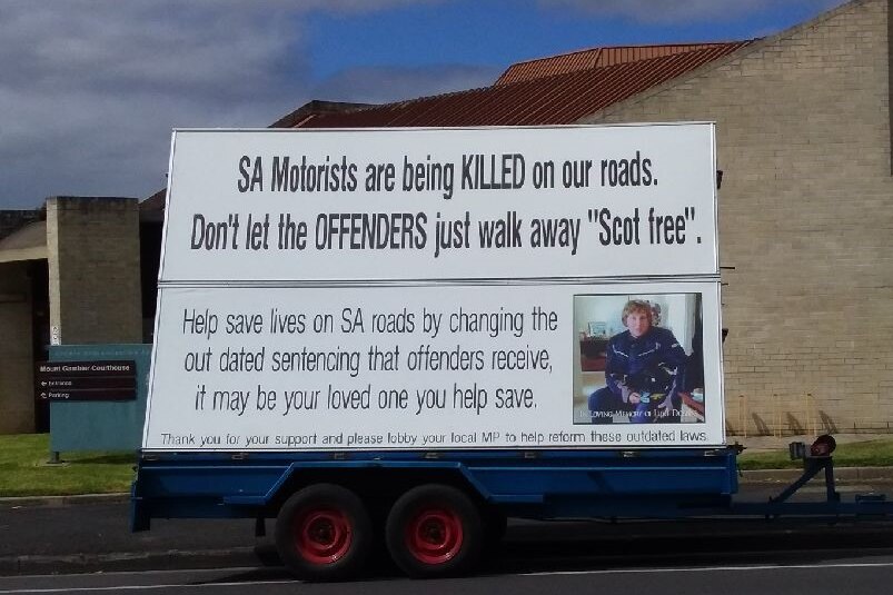 A large billboard attached to the back of a trailer. The words call for stronger sentencing for killer drivers.