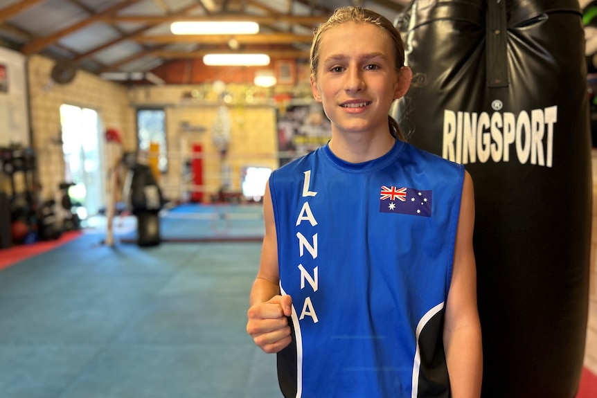 A teenage boy stands inside a boxing gym.