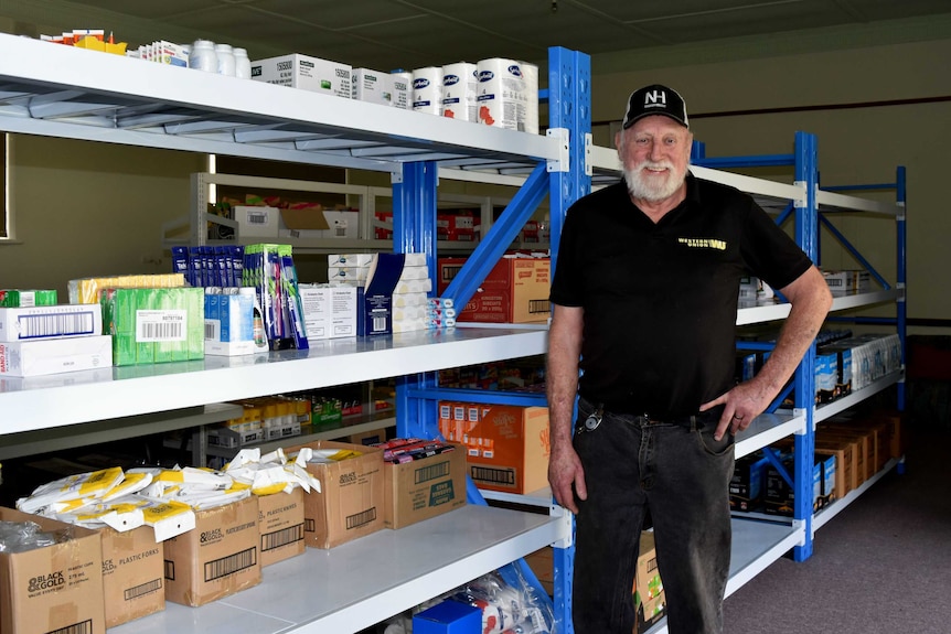 Geoff Robinson is standing next to shelves of groceries in the pop up supermarket in Lucindale