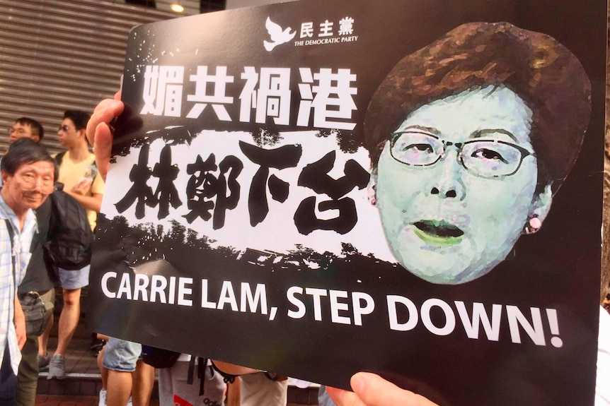 Pengunjuk rasa memegang poster meminta Carrie Lam untuk mundur saat unjuk rasa terjadi di bulan Juni.