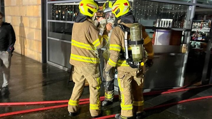 Firefighters wear breathing apparatus outside a building