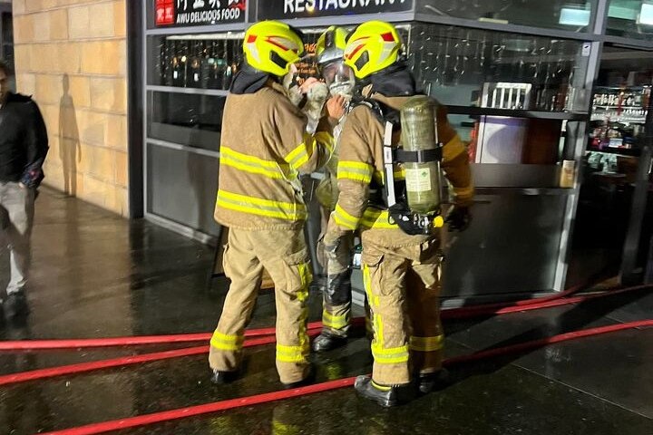 Firefighters wear breathing apparatus outside a building