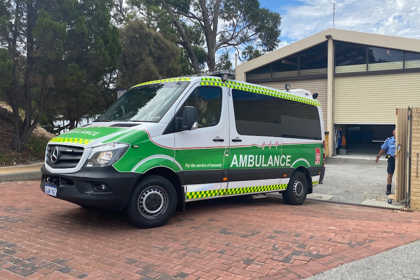 a green and white ambulance van drives on to paved road