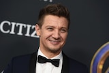 Jeremy Renner in a tuxedo smiles on the red carpet for the Avengers Endgame premiere