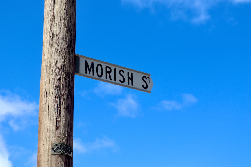 A wooden pole with a street sign saying "morish street" on a sunny day. 