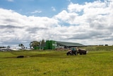 Farmer Mark Trigg spraying cow manure across his pastures, with the biodigester in the background.