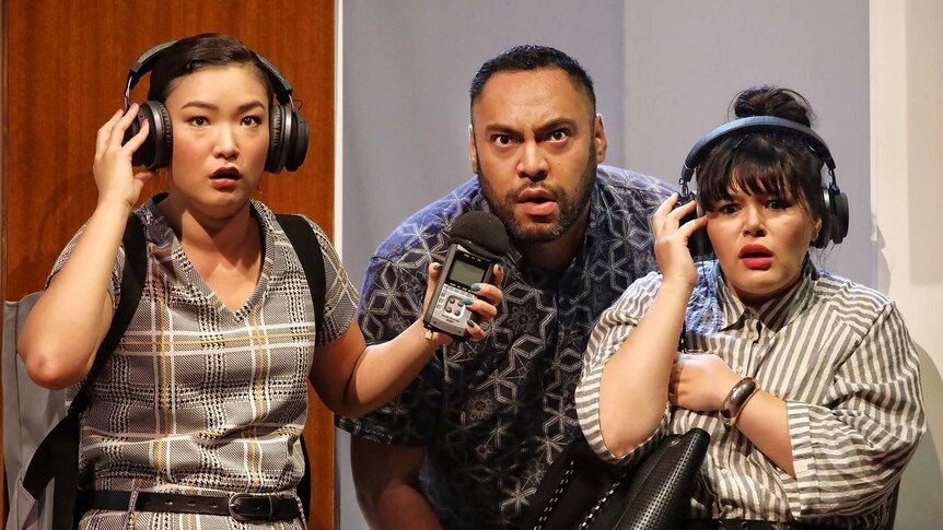Looking worried, Michelle Lim Davidson (left) and Nakkiah Lui (right) listen to headphones. Anthony Taufa stands between them.