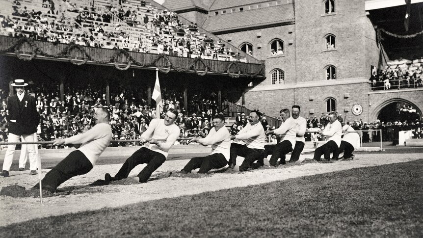 A black and white picture of a team participating in a tug of war. 