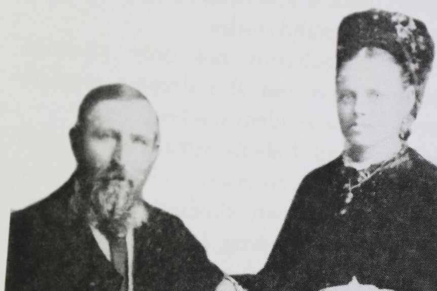 Old fashioned photograph of couple from early 1900s posing on chair