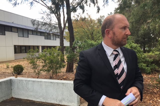 A man in a suit standing outside an office building.