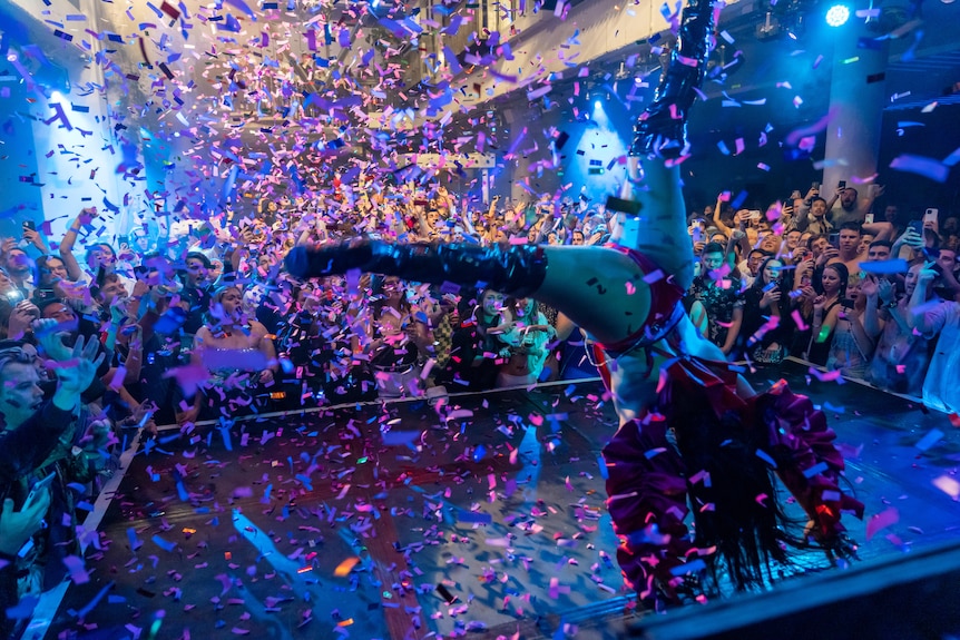 Kween Kong turns a cartwheel onstage as confetti rains down and the audience watches.