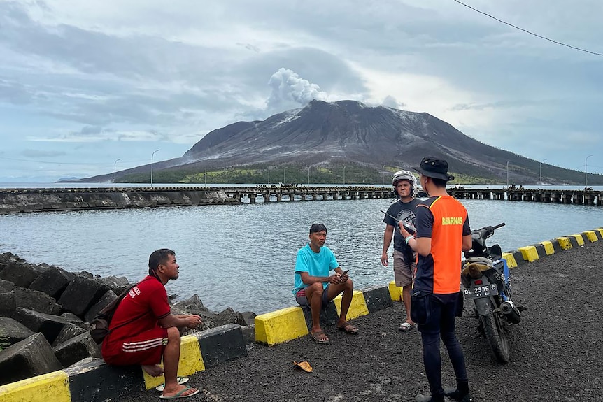 People talking with a volcano in the background. 