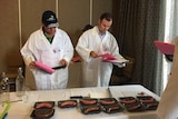 Judges observe several sausage offerings at a best butcher competition.