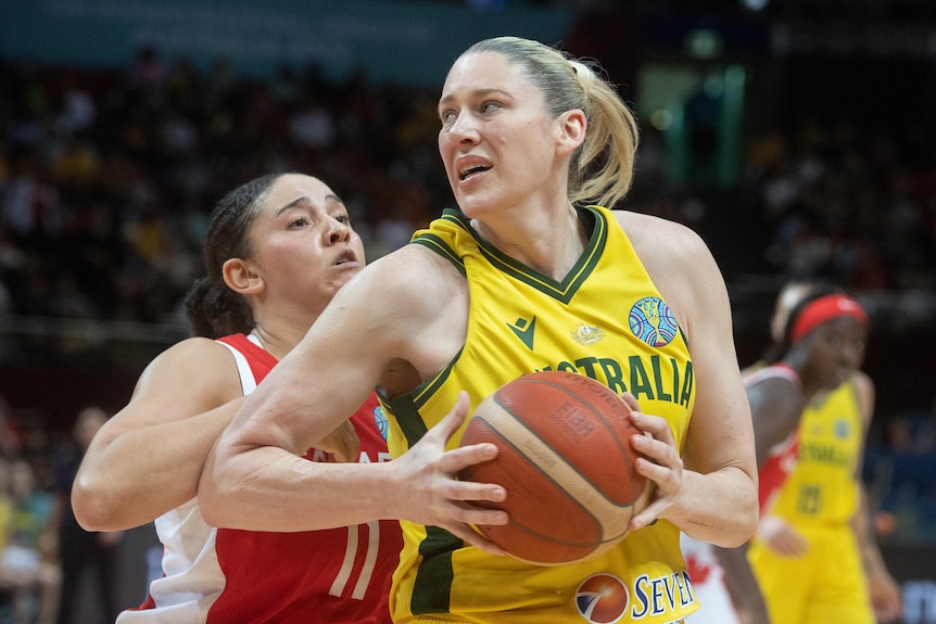 Lauren Jackson holds onto a basketball and grimaces with an opponent behind her
