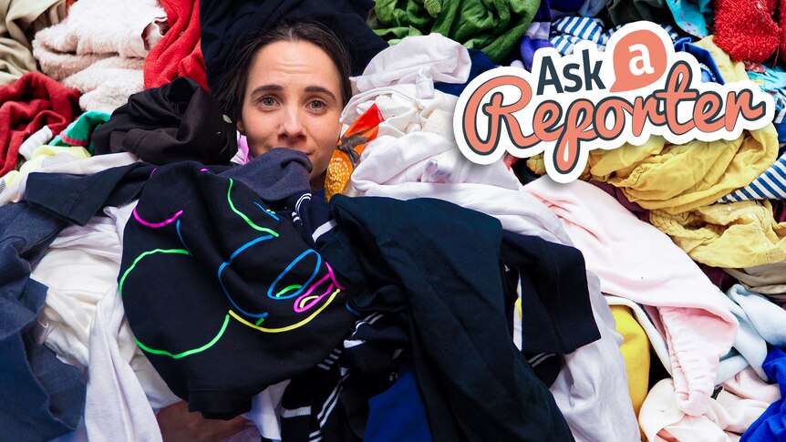 Justina peeking through a pile of clothes.