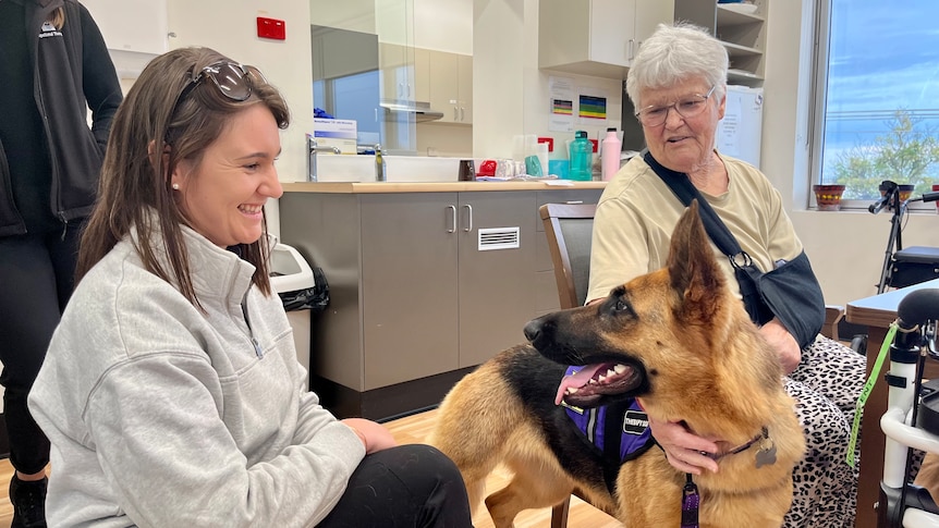 A hospital patient with a therapy dog and handler.