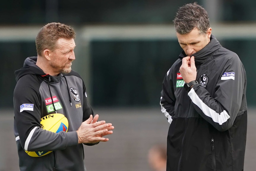 A mid shot of Magpies head coach Nathan Buckley speaking to assistant coach Justin Longmuir at training.