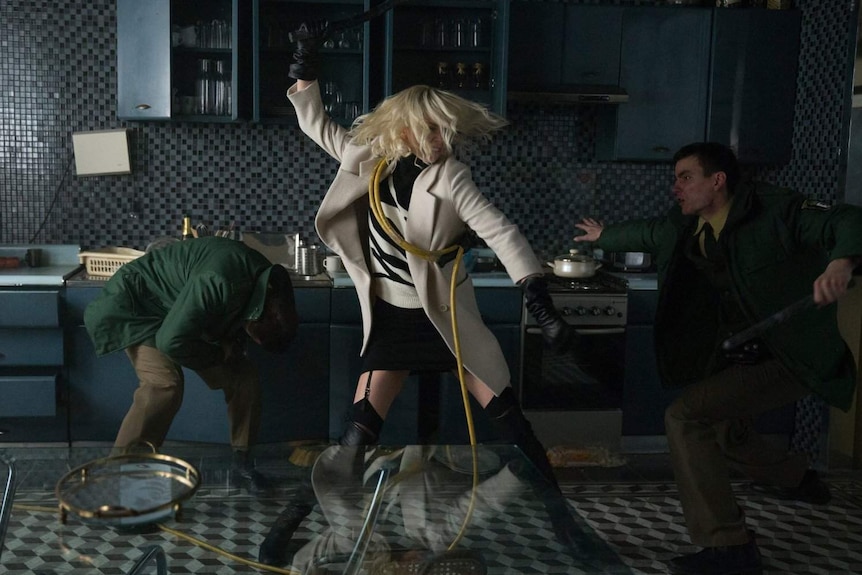 Still image from the film Atomic Blonde where Charlize Theron fights two enemies in a kitchen.