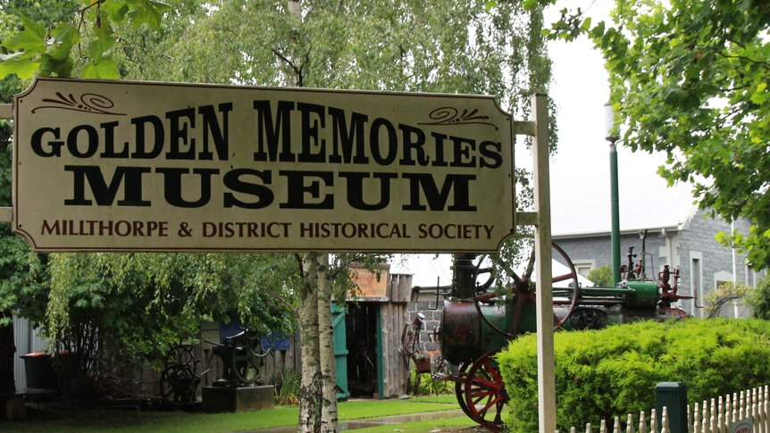 Sign with golden memories museum written on it surrounded by green trees