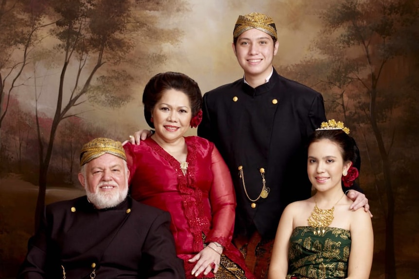 A Caucasian man with his Indonesian wife and two children posing in traditional Javanese outfit.