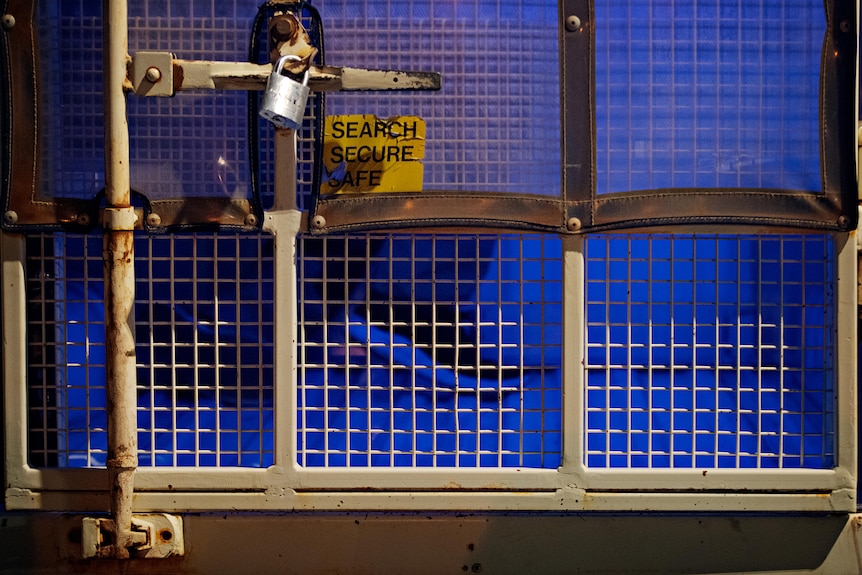 A person in the back of a police wagon. 