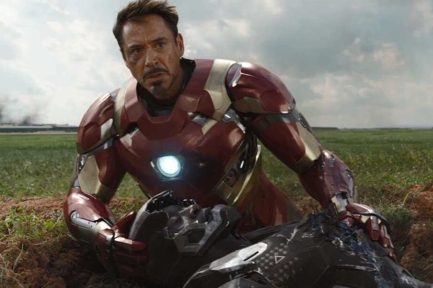 Tony Stark holds Rhodey on the ground.