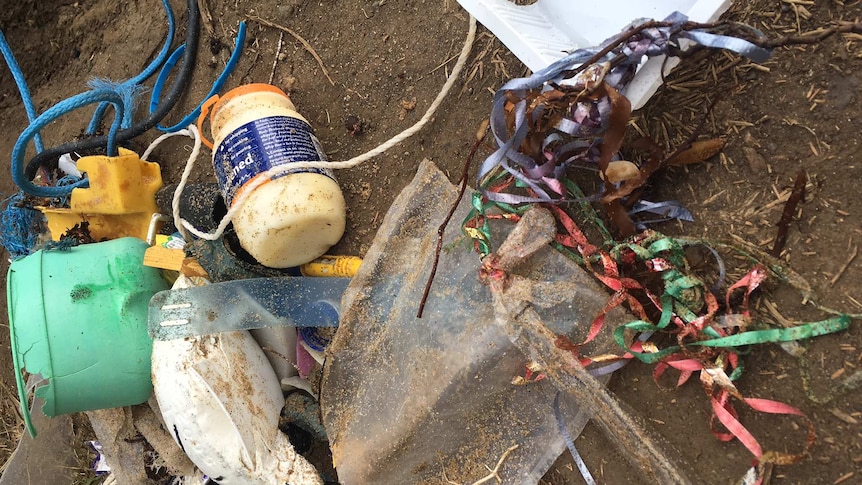 A jumble of rubbish, including balloon scraps on brown dirt
