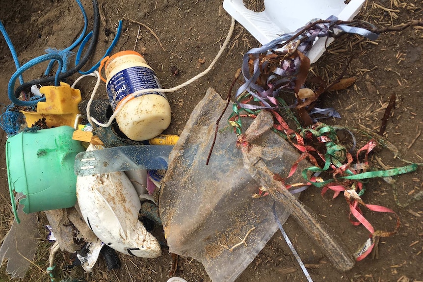 A jumble of rubbish, including balloon scraps on brown dirt