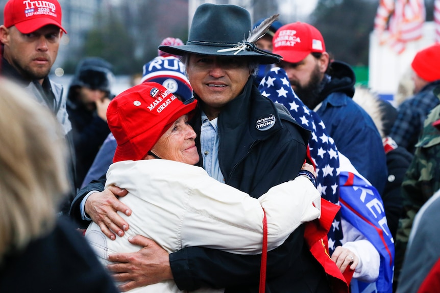 A man and a woman hug at a rally for supporters of Donald Trump.