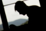 Young male silhouetted against window.