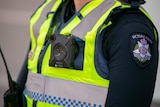 A square body camera worn on the yellow vest of an unidentified Victoria Police officer.