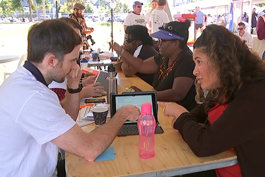 People sitting at a table looking at an iPad.