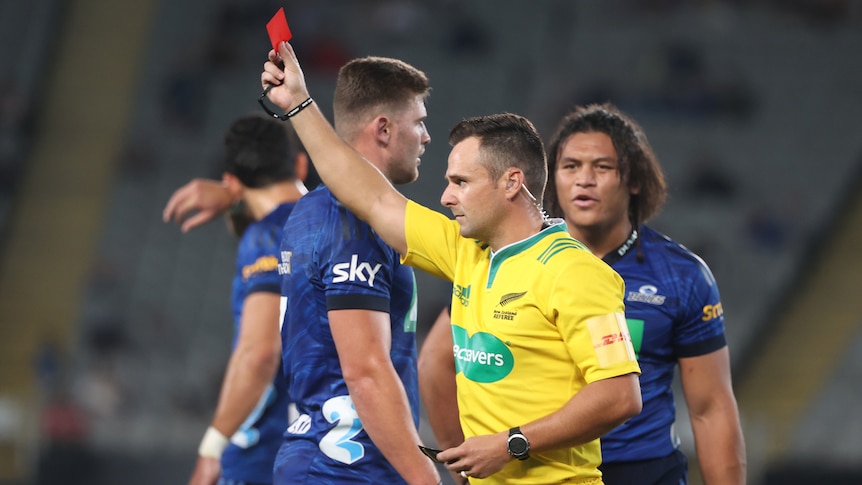 A Super Rugby Pacific referee holds up a red card during a match in the 2022 season.