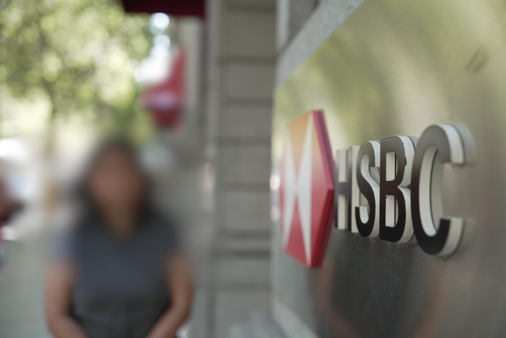 Una mujer asiática no identificada se encuentra afuera de una sucursal del banco HSBC. 