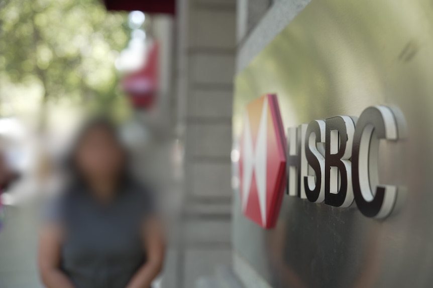 Una mujer asiática no identificada se encuentra afuera de una sucursal del banco HSBC. 