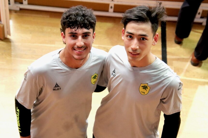 Two young men in soccer shirts smile at the camera