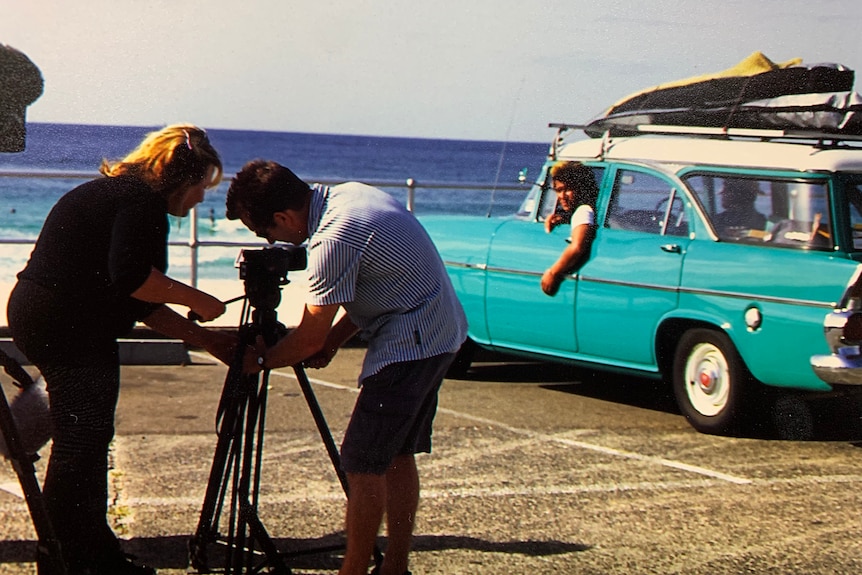 Woman and man positioning the camera while filming yuto in the holden at Bondi Beach
