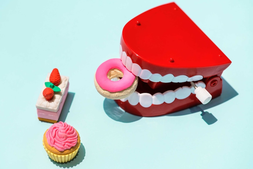 Plastic teeth surrounded by models of sugary treats.