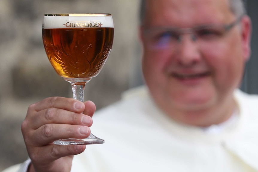 Norbertine Father Karel poses with a Grimbergen beer, symbolised by a phoenix.