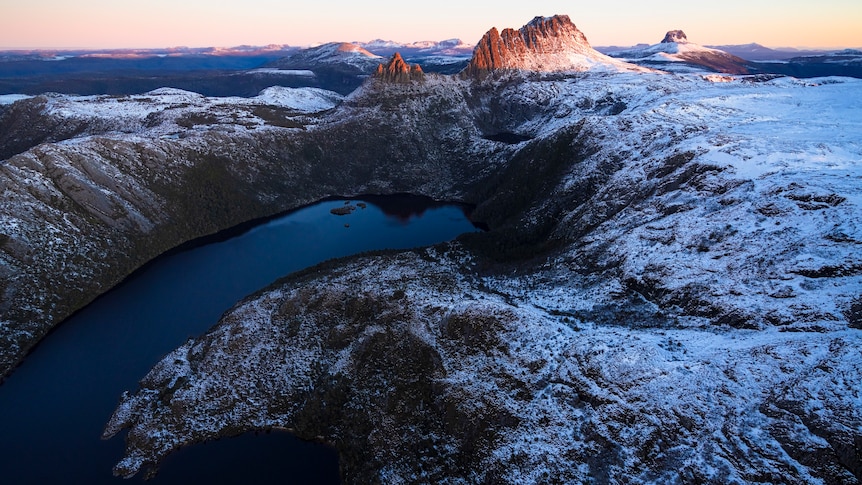 An aerial view of a snow-covered landscape,including a mountain and a lake